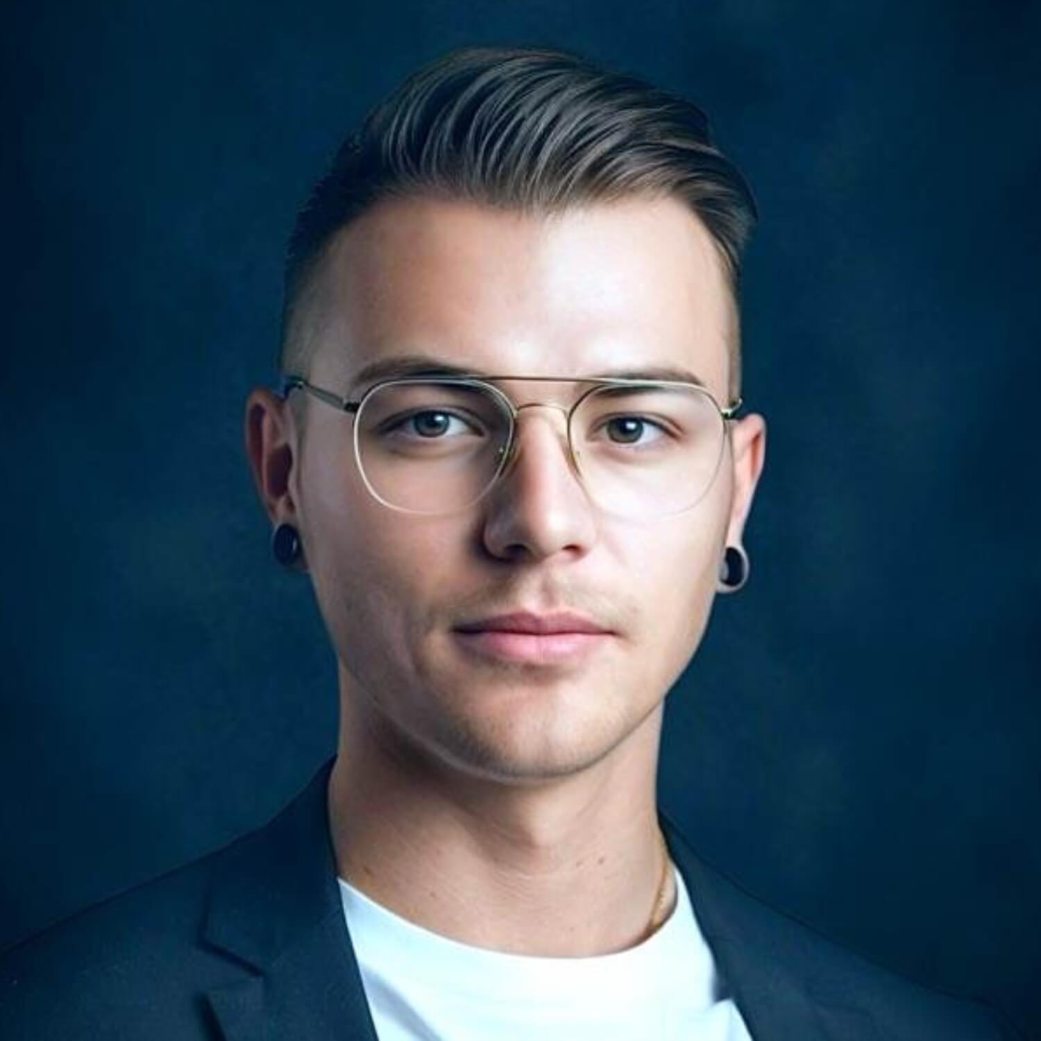 Nahaufnahme eines jungen Mannes mit Brille und kurzem Seitenschnitt vor blauem Hintergrund, neutraler Blick.