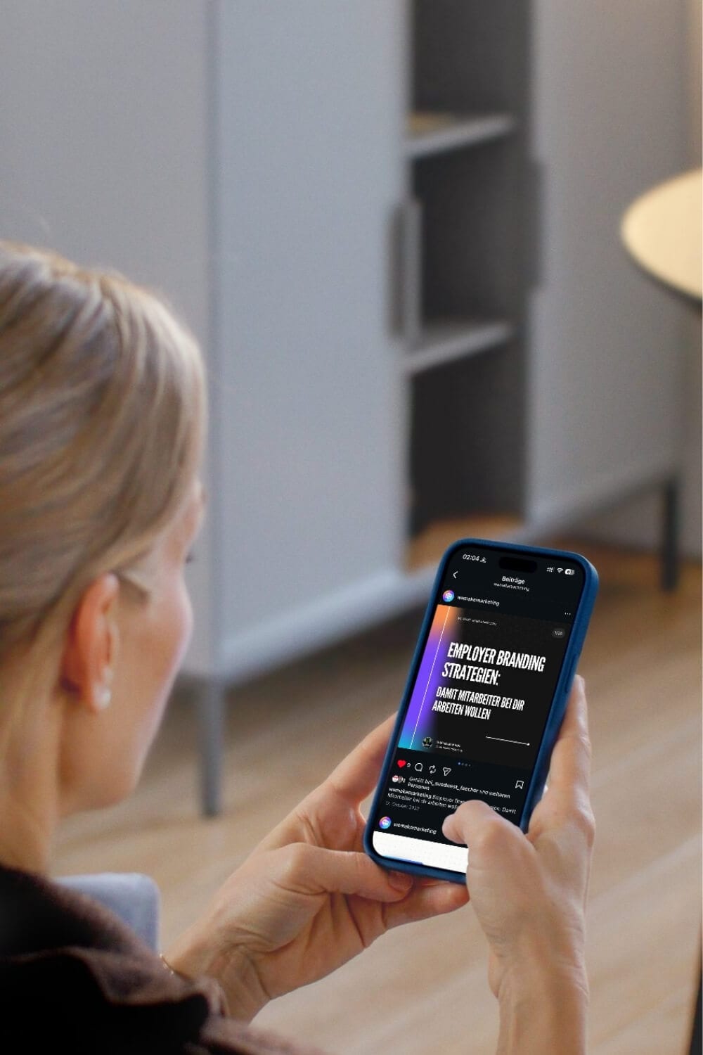 Person hält ein Smartphone und liest einen Beitrag über Employer-Branding-Strategien im Social-Media-Feed.